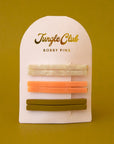 On a white packaging is six bobby pin clips in three different colors. From top to bottom is an ivory shell shade, mango orange, and olive green shade.