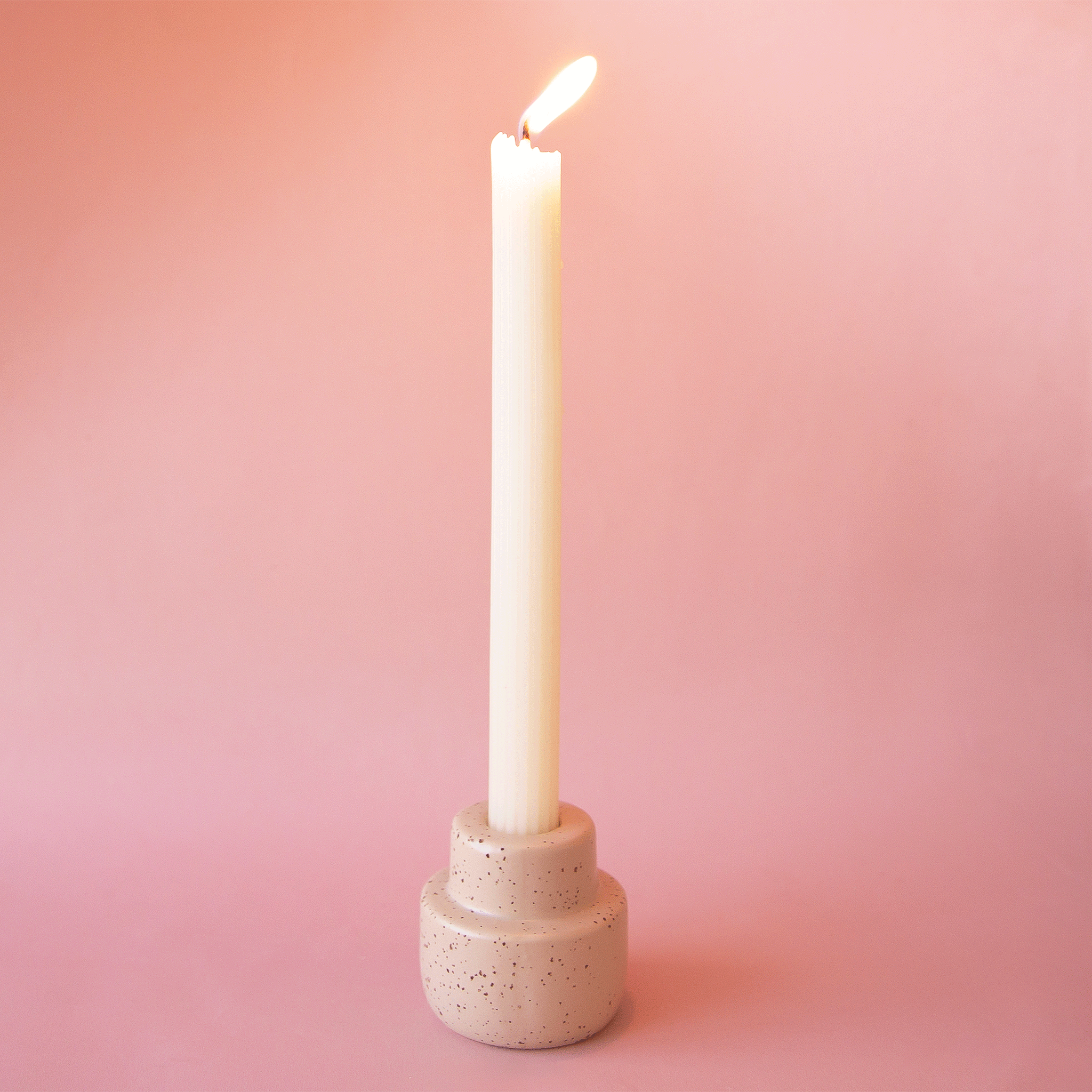 The peach colored ceramic candleholder with a taper candle in the center.