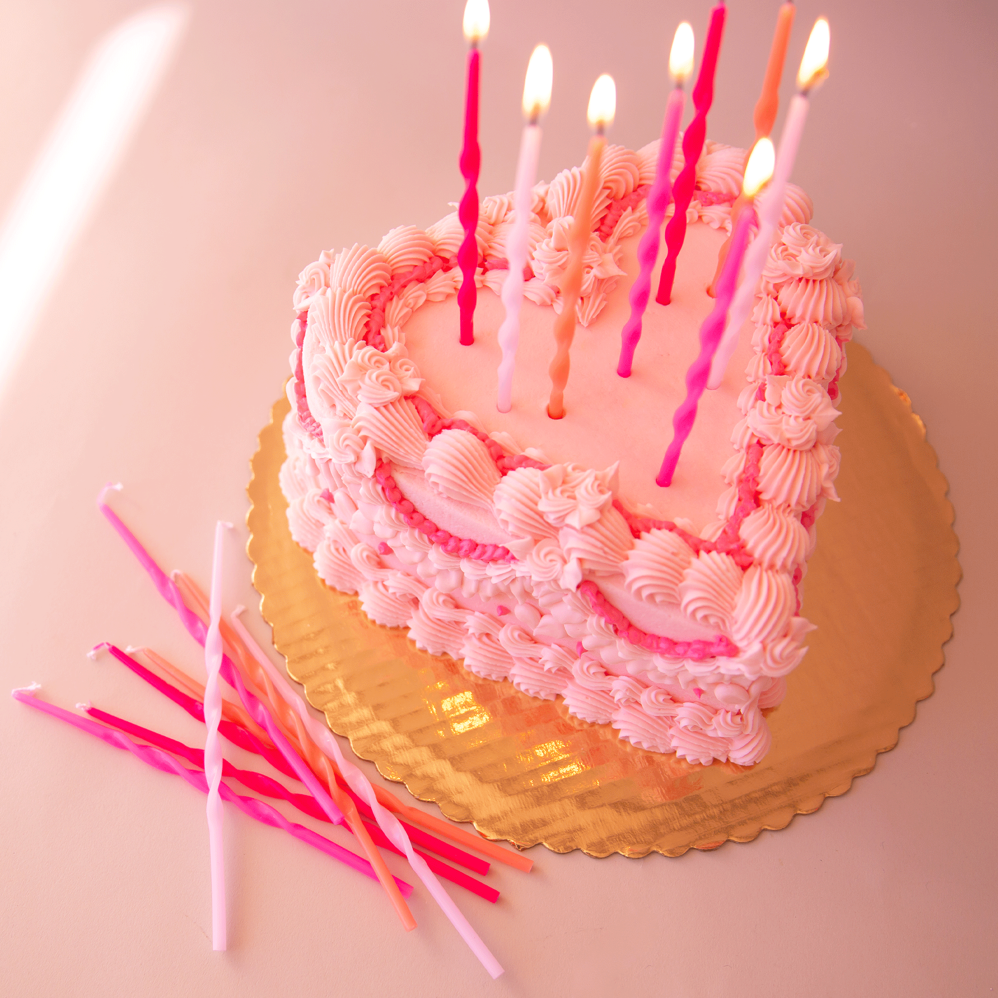 On a pink background and on a pink cake is a variety of long pink twisted candles. Cake and props not included with purchase. 