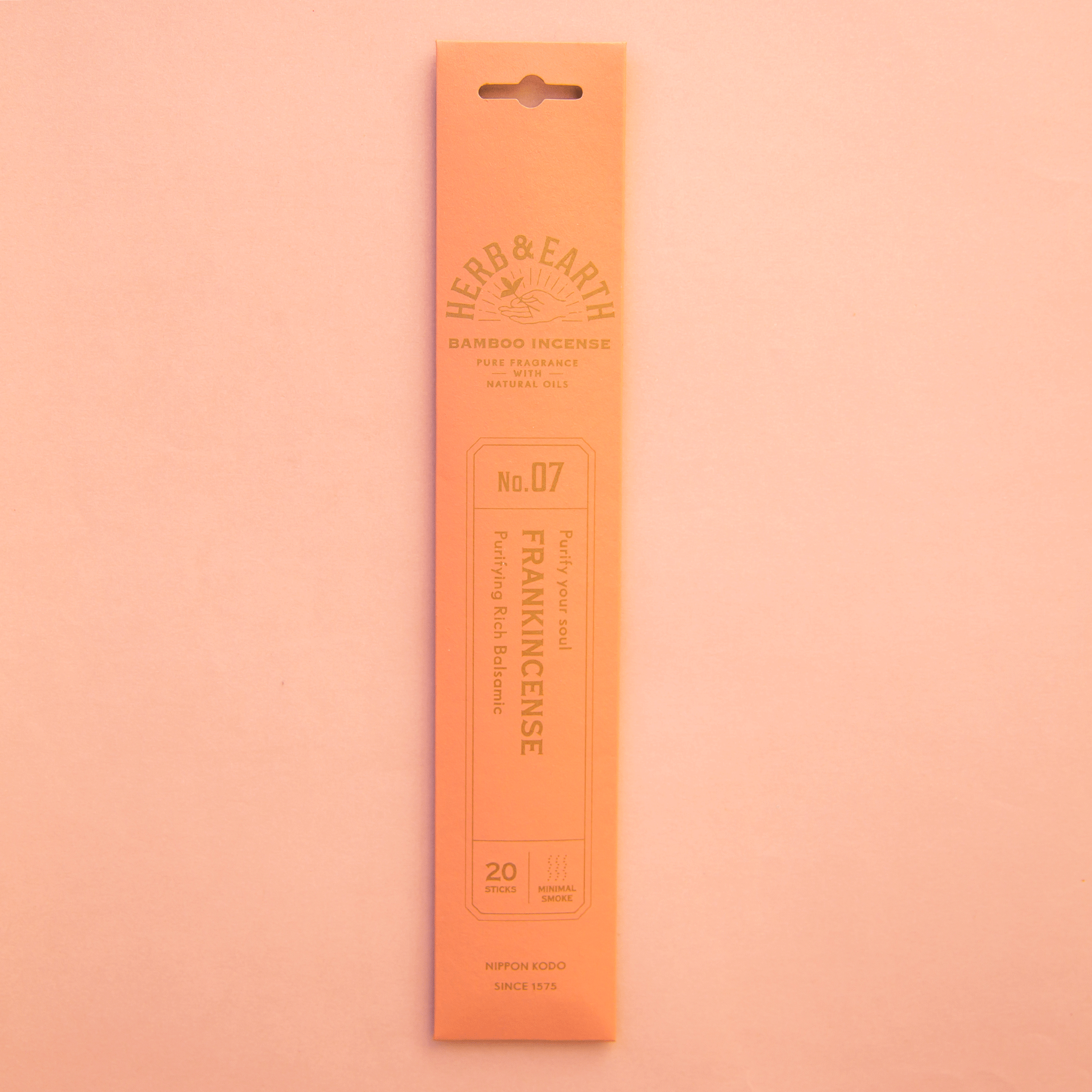 On a peach background is a peachy colored packaging filled with frankincense incense. 