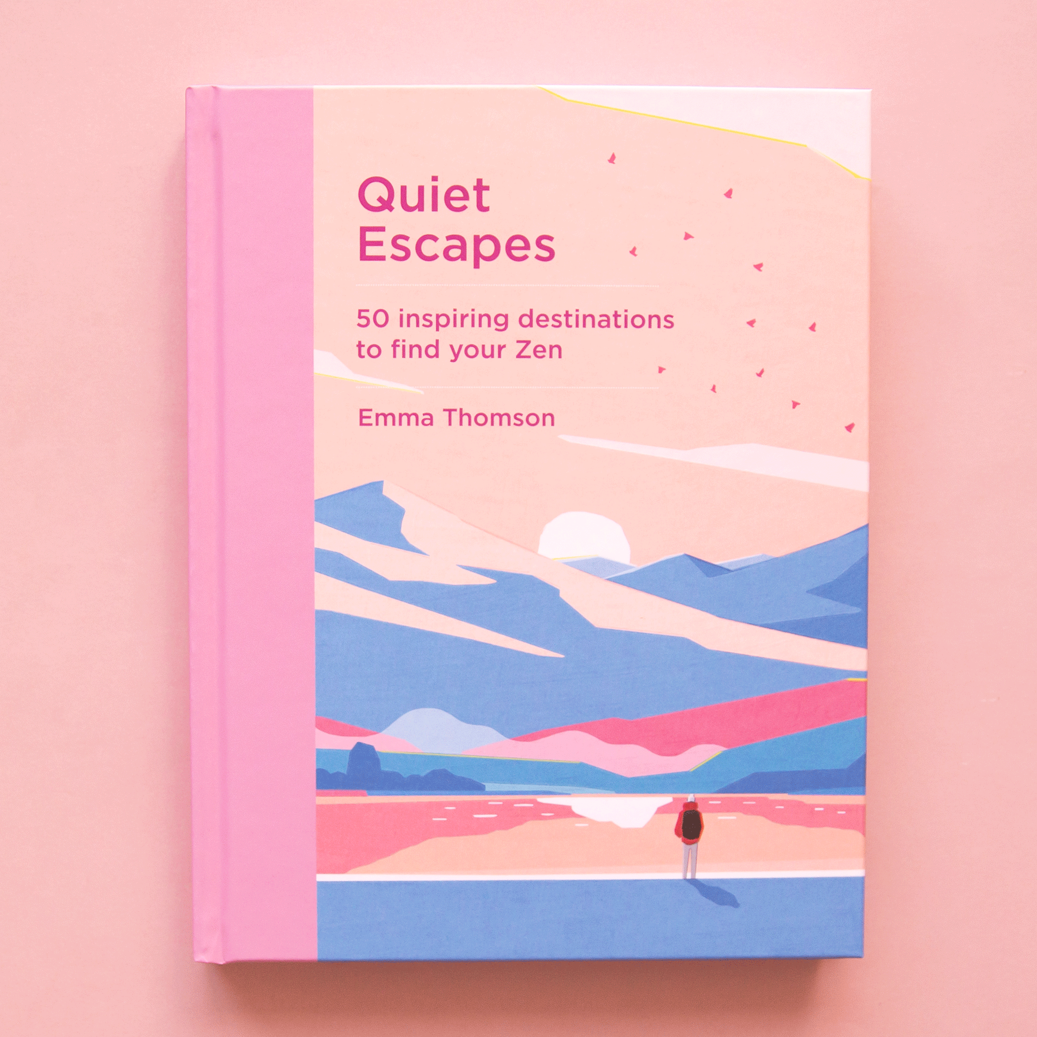 On a peach background is a book with a blue, pink and tan book cover with a mountainous landscape graphic and a title that reads, "Quiet Escapes 50 inspiring destinations to find your Zen". 