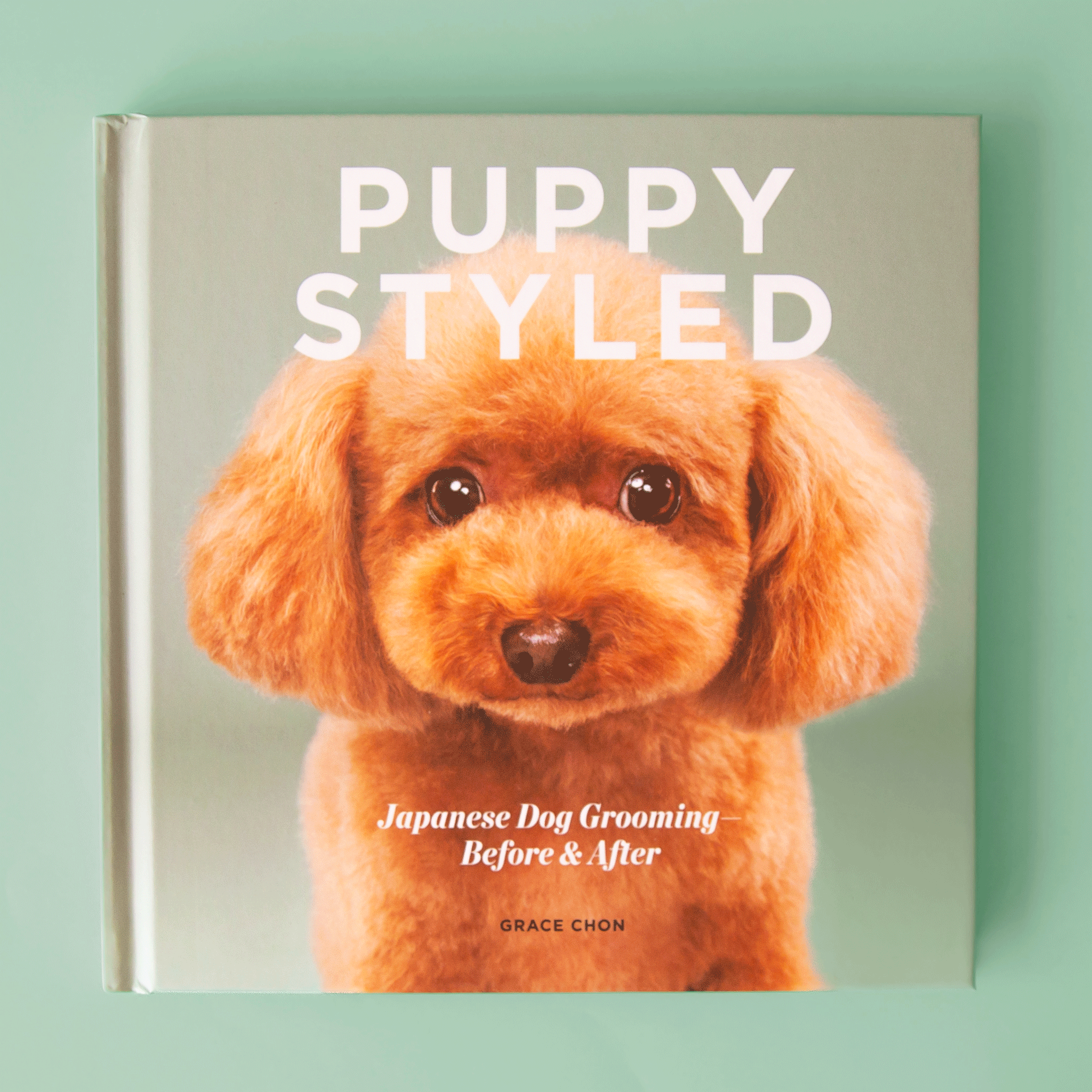 On a green background is a light sage book with a fluffy puppy photo on the front and a white title that reads, "Puppy Styled". 