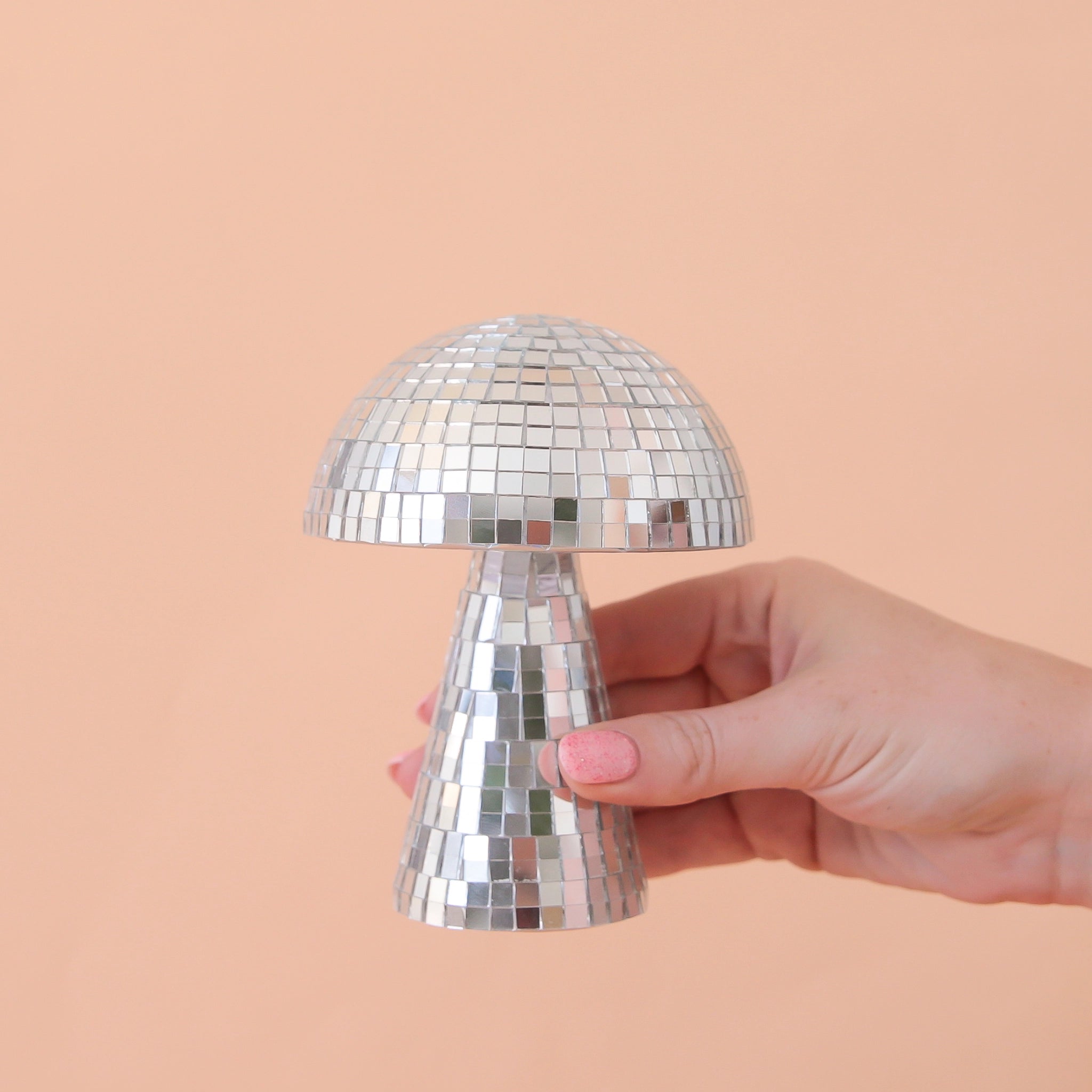 On a peach background is a disco mushrooms with mirrored square pieces all over.