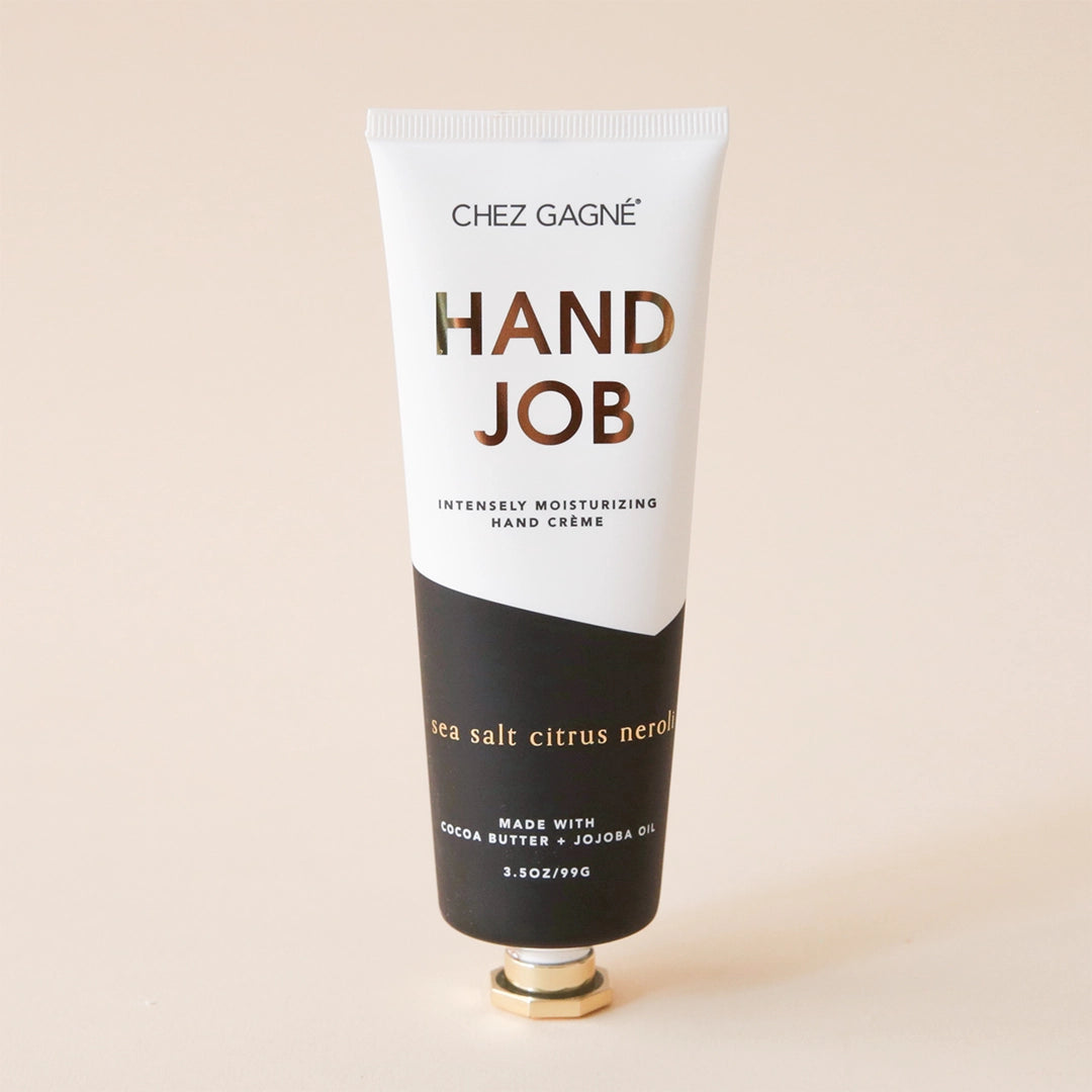 On a white background is a tube of hand cream that is half black and half white along with gold text that reads, "Hand Job" as well as black text underneath that reads, "Intensely moisturizing hand crème.