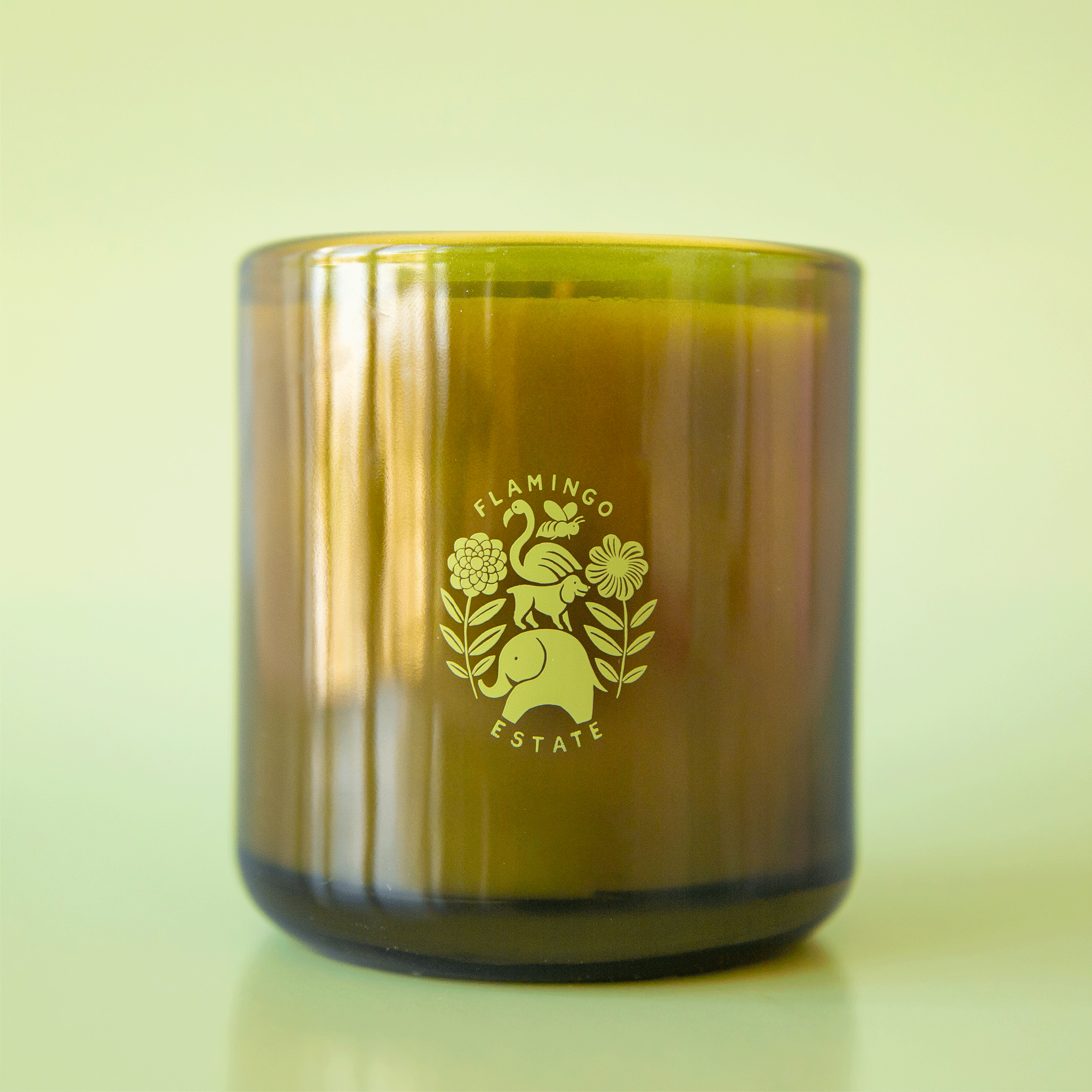 On a green background is a green glass jar candle with a logo in the center that reads, "Flamingo Estate".