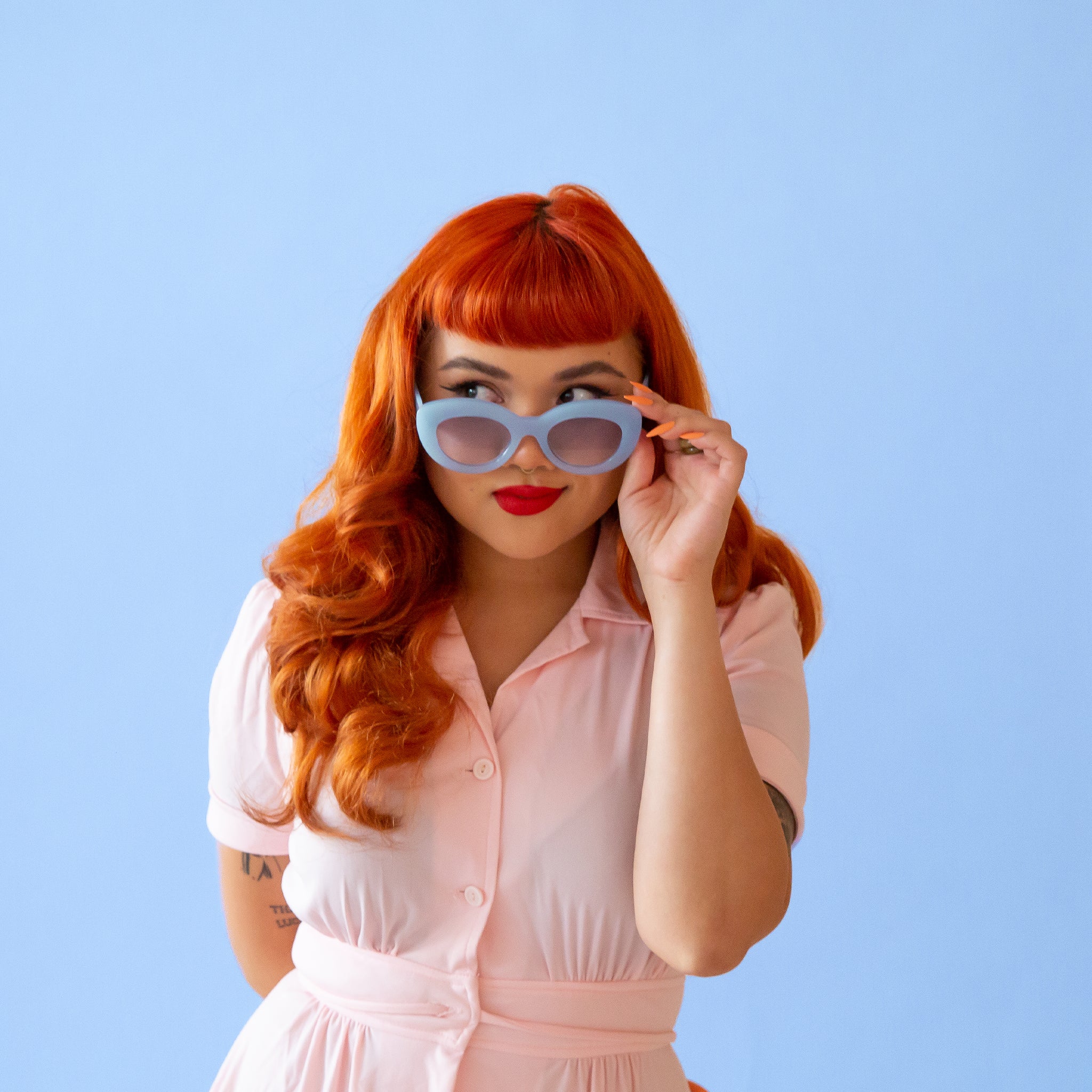 On a blue background is a model wearing the Gemma Sunglasses in the shade Lapis.