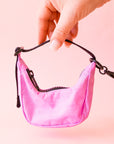A small crescent bag charm in a pink shade with black straps and zipper. 