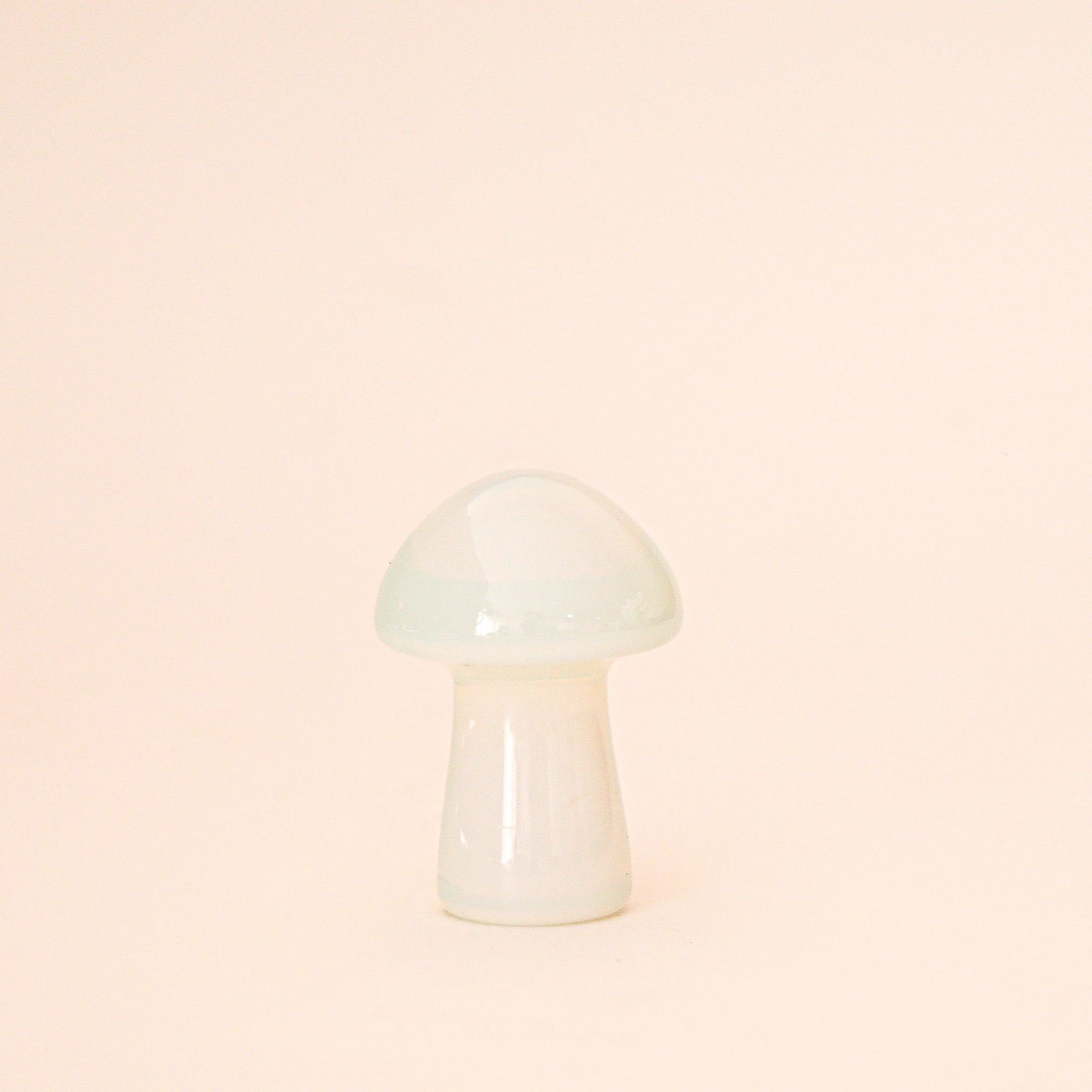 On a pink background is the larger version of the mushroom shaped opal crystal. 
