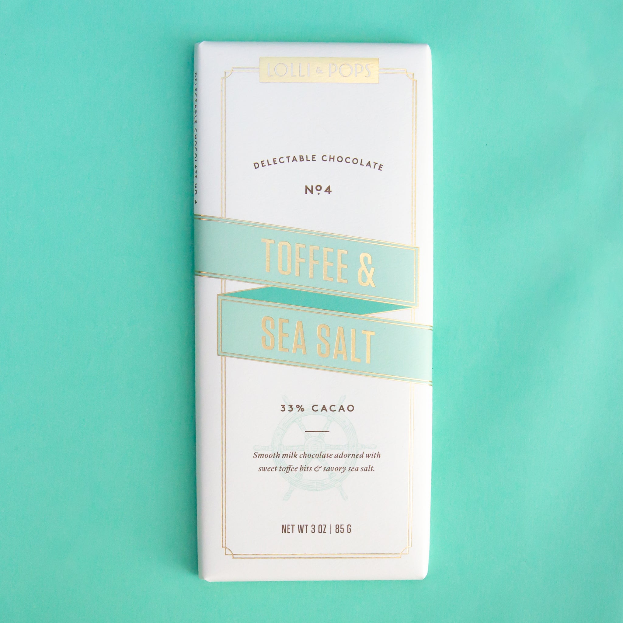On a teal background is a neutral colored package of a chocolate bar with toffee and sea salt.