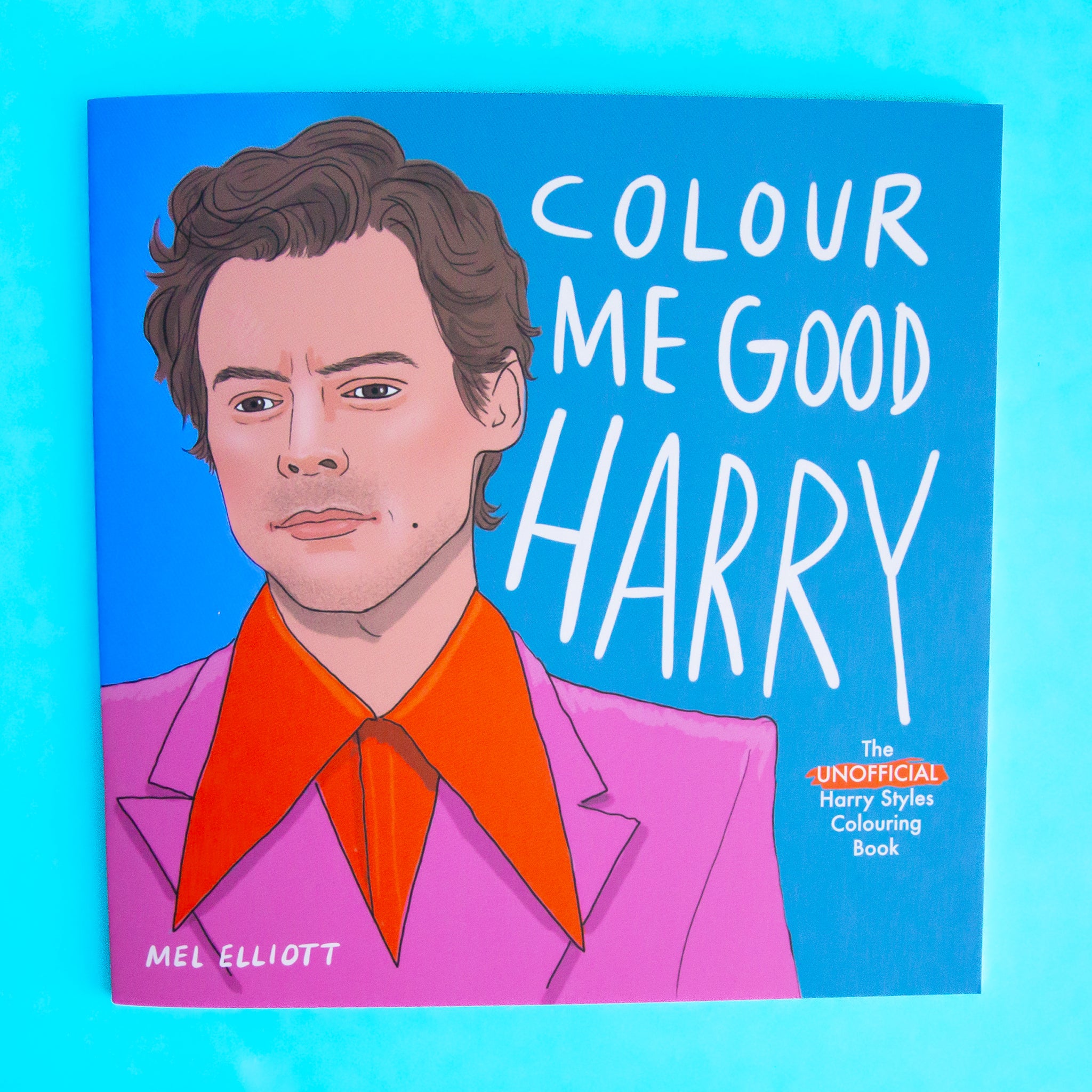 On a blue background is a blue coloring book cover with an illustration of Harry Styles and text that reads, &quot;Colour Me Good Harry&quot;.