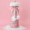 On a pink background is a pink sequin wine gift bag with fuzzy white details and a pom pom pink bow. 
