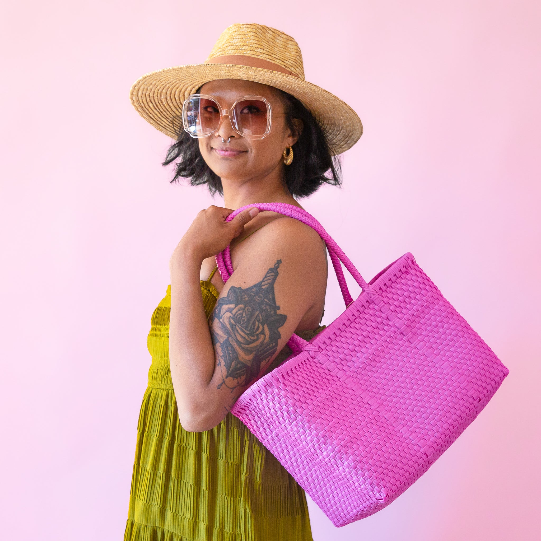 On a pink background is a hot pink woven bag. 
