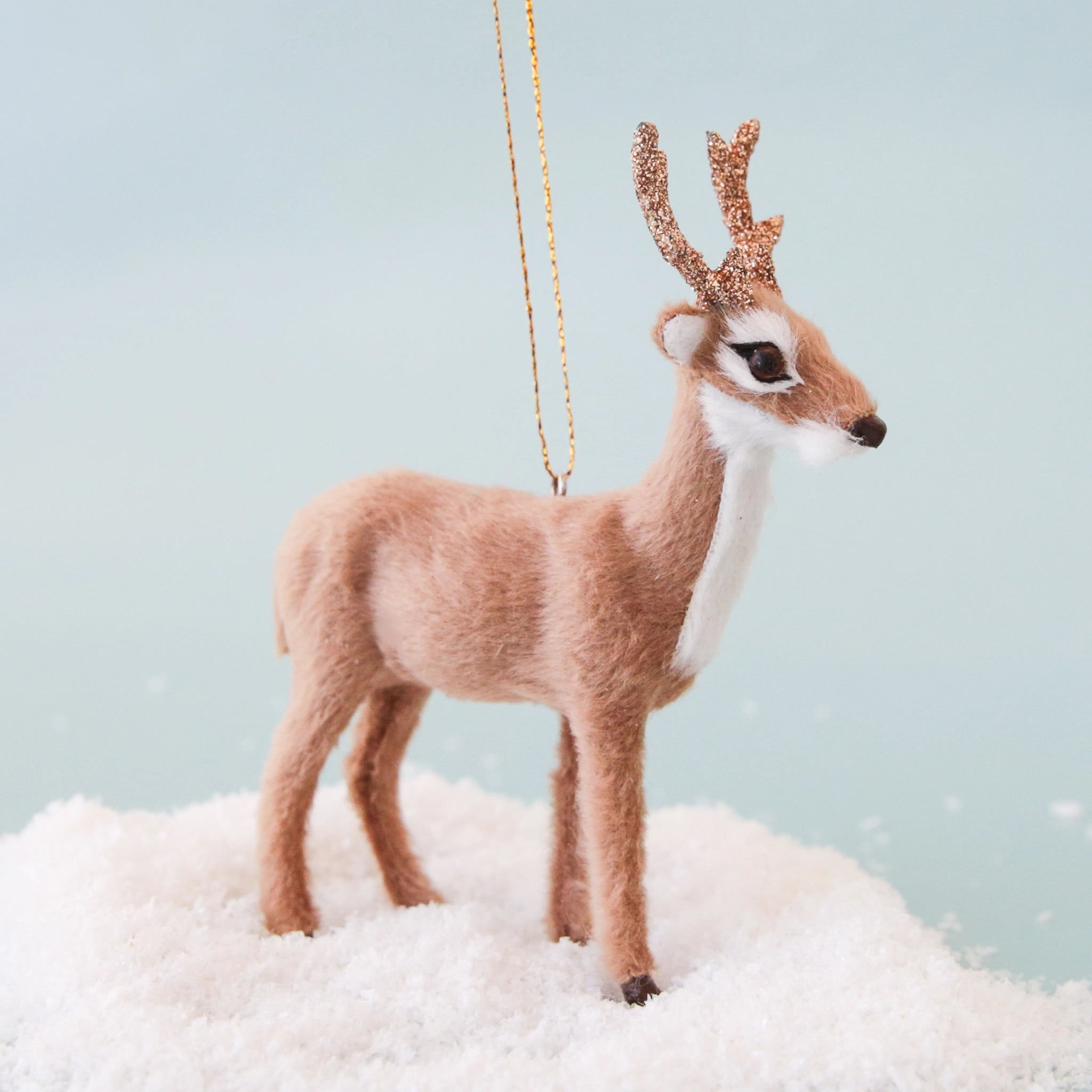 A furry white and brown stag holiday decor with glitter antlers.
