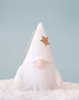 On a blue background is the velour gnome ornament with a white hat and a white beard as well as a gold glitter star on the hat.  