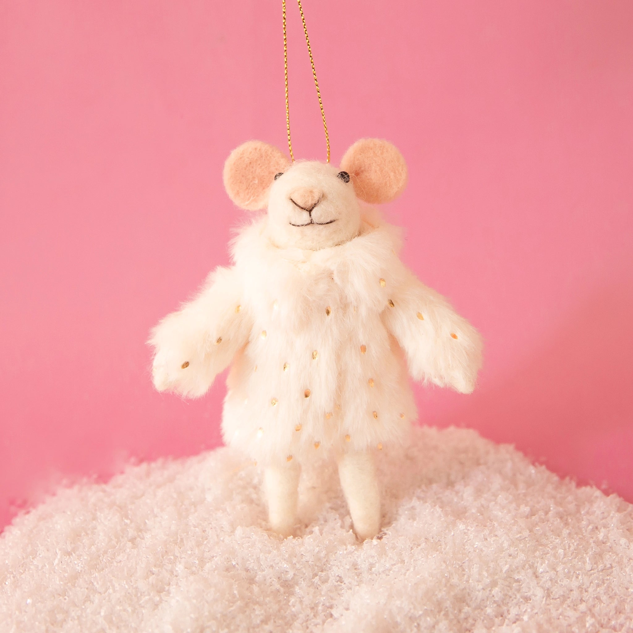 On a pink background is a white felt mouse ornament wearing a faux fur jacket. 