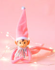 An adorable pink elf wearing a pink tall hat with silver tinsel around its neck.
