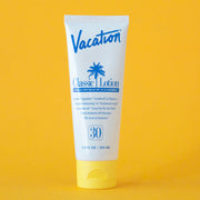 On a yellow background is a white squeeze tube of sunscreen with a yellow lid and a blue text that reads, "Vacation Classic Lotion SPF 30" along with a blue palm design in the center.