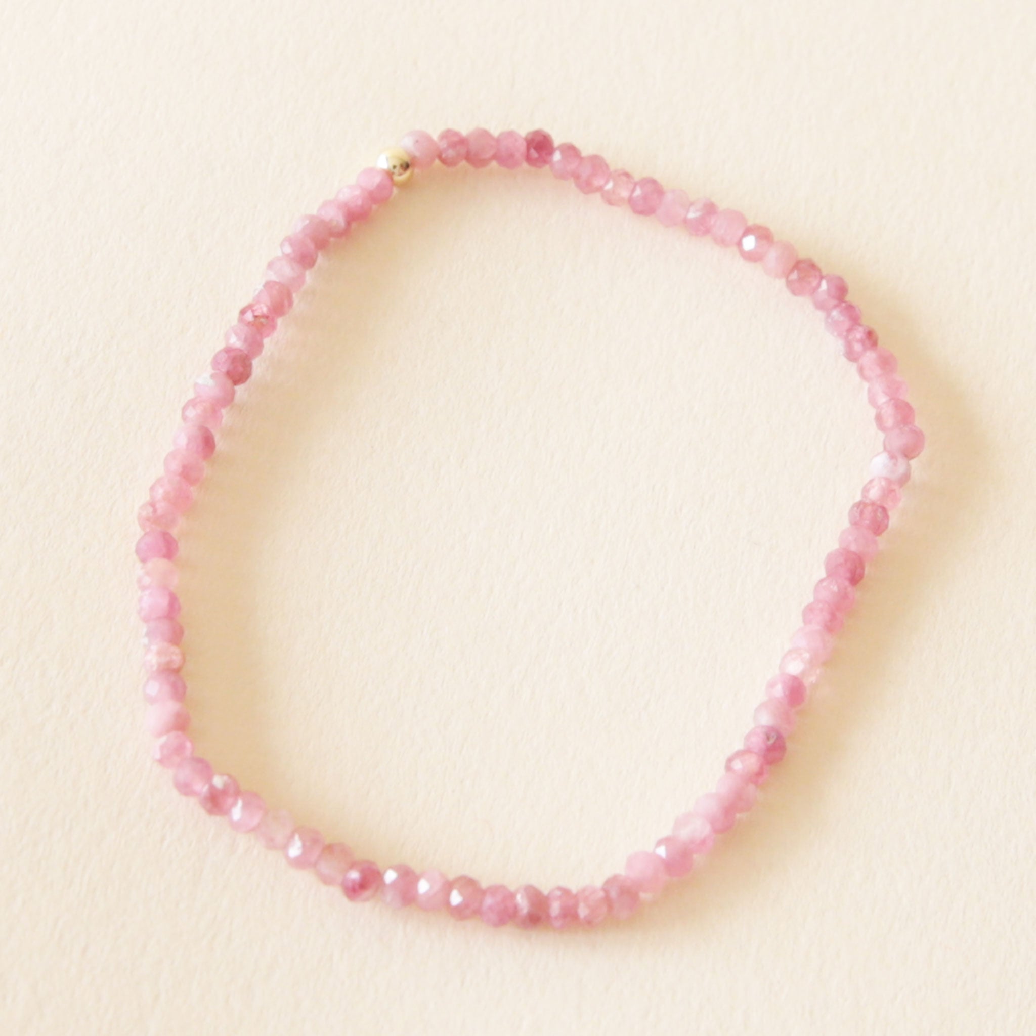 On a neutral background is a pink tourmaline beaded bracelet. 