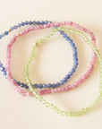 Three different colored bead bracelets on a neutral background. 