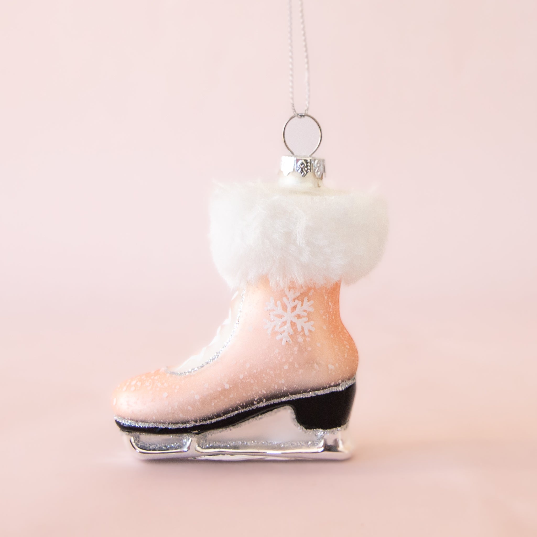 A light pink ice skate shaped ornament with a faux fur trim.