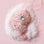 On a pink background is a pink flower shaped ornament with rhinestones all over.