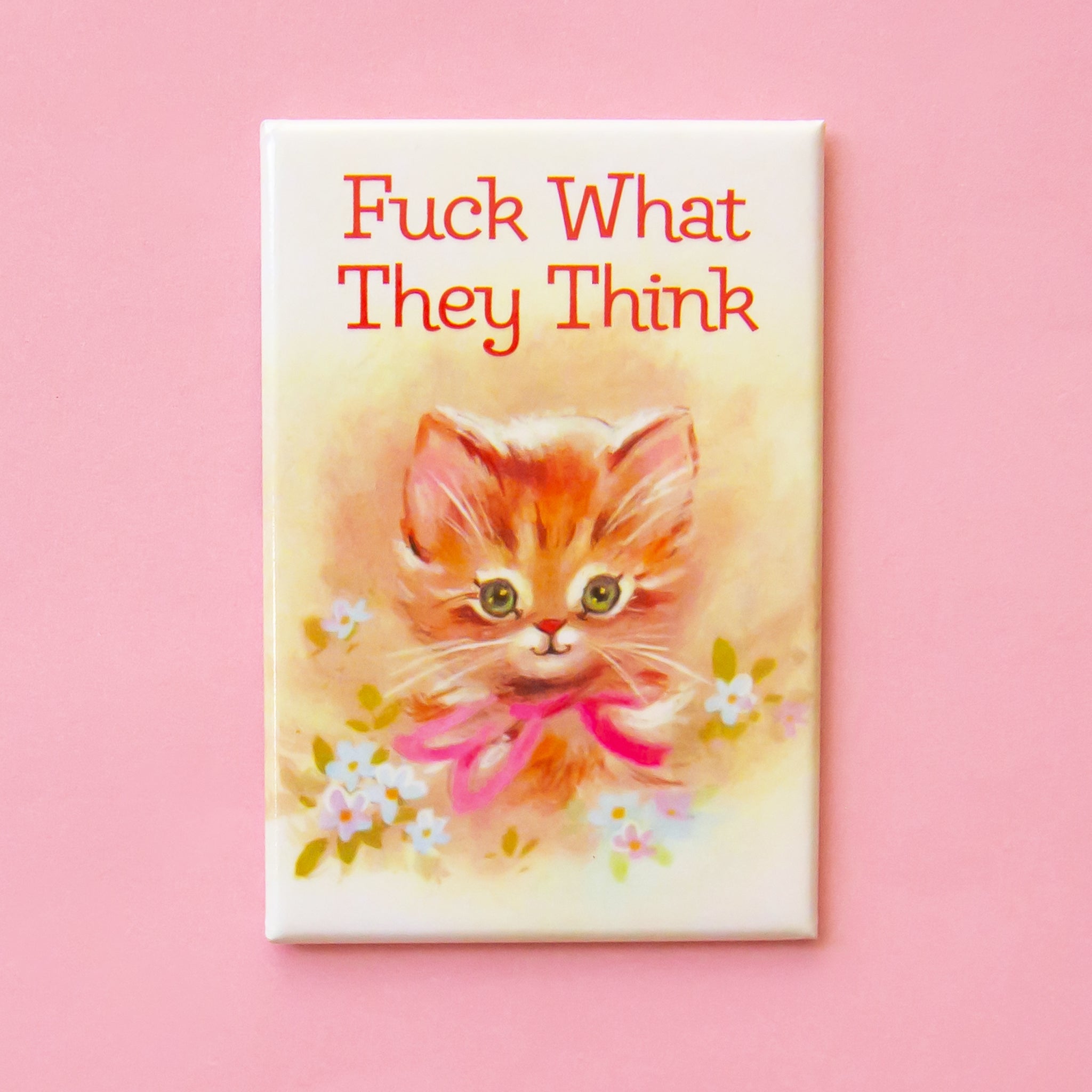 On a pink background is a magnet with an illustration of a kitten and florals around it and text above that reads, "Fuck What They Think". 