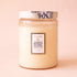 A decorative jar glass candle with a lid and label that reads, "Jasmine Midnight Blooms". 