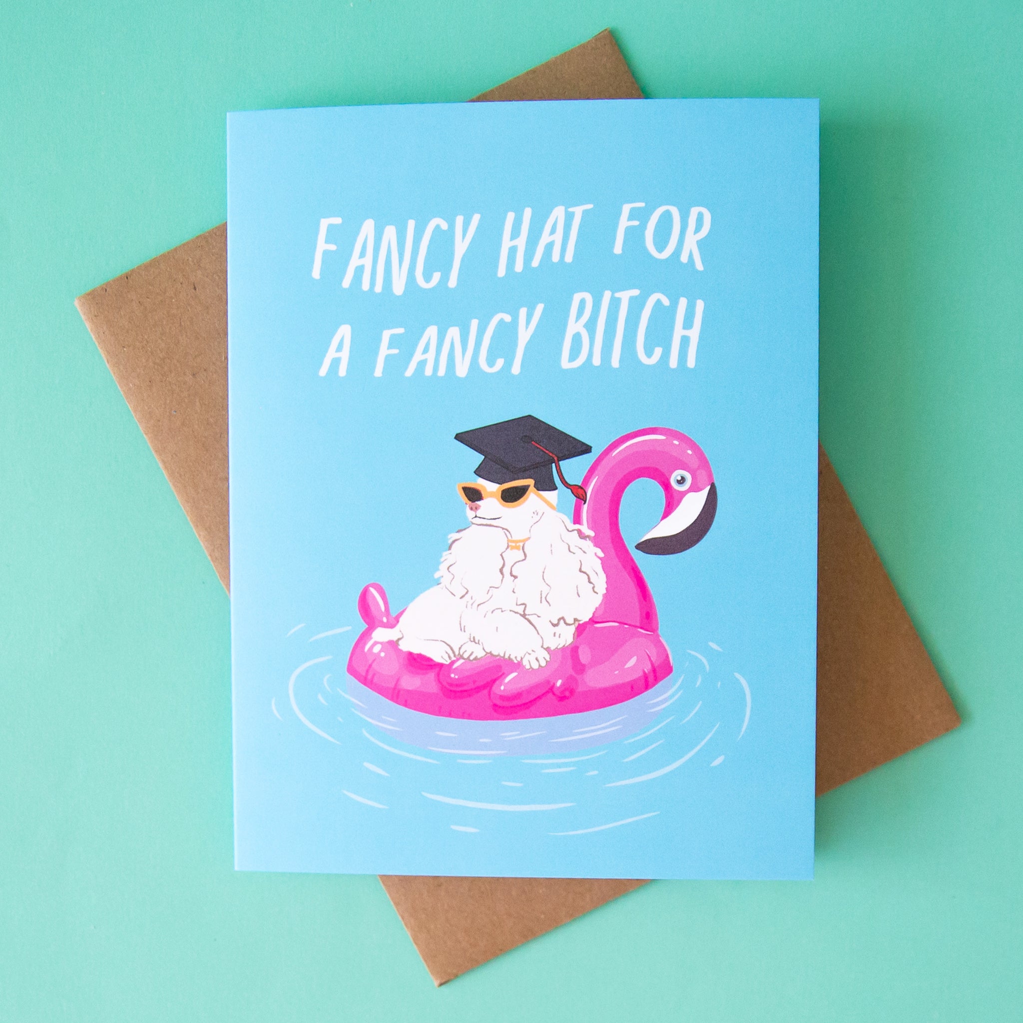 On an aqua background is a blue card with a dog in a pink floaty and wearing a black graduation cap with white text above that reads, "Fancy Hat For A Fancy Bitch". 