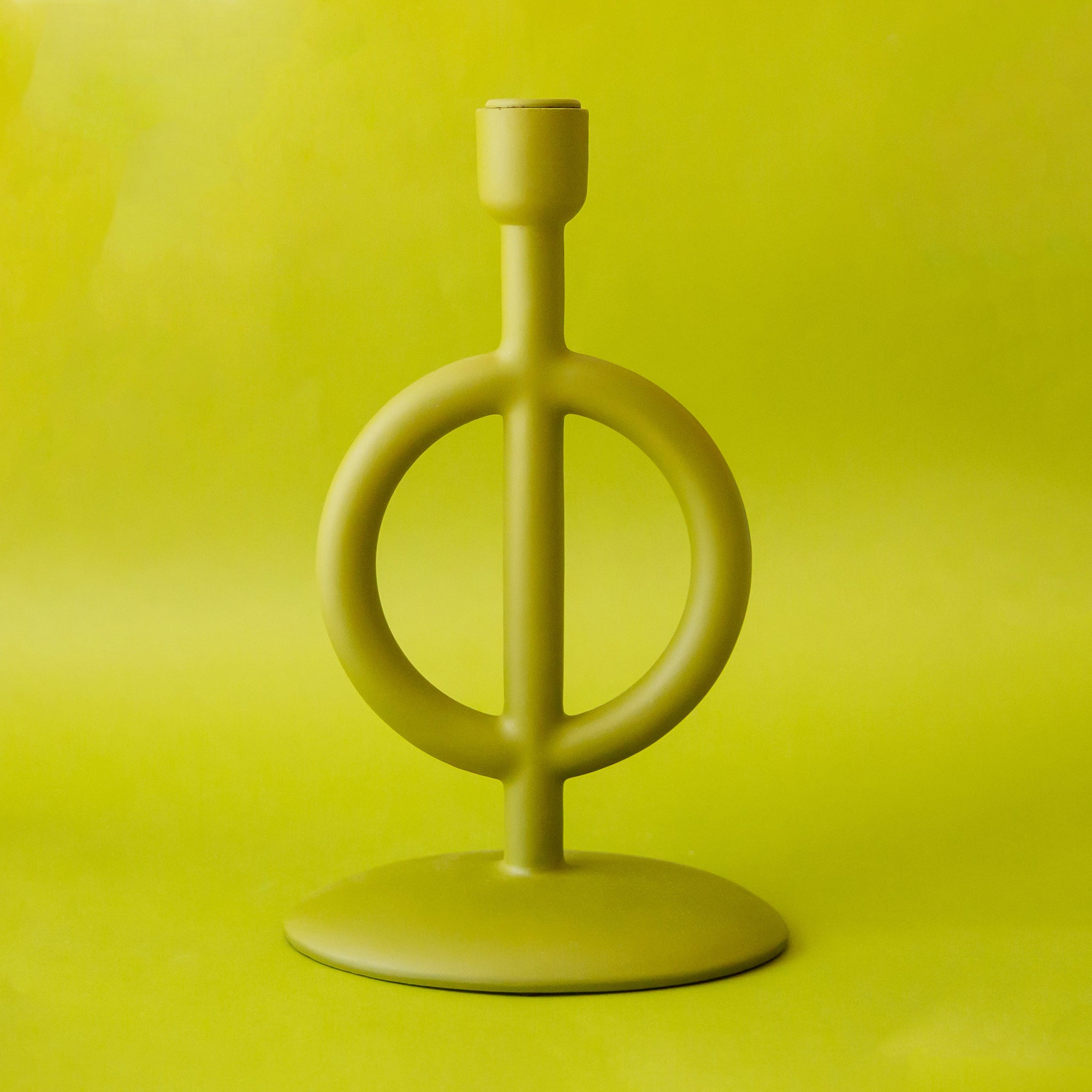 A green taper candle holder with a circle base. 