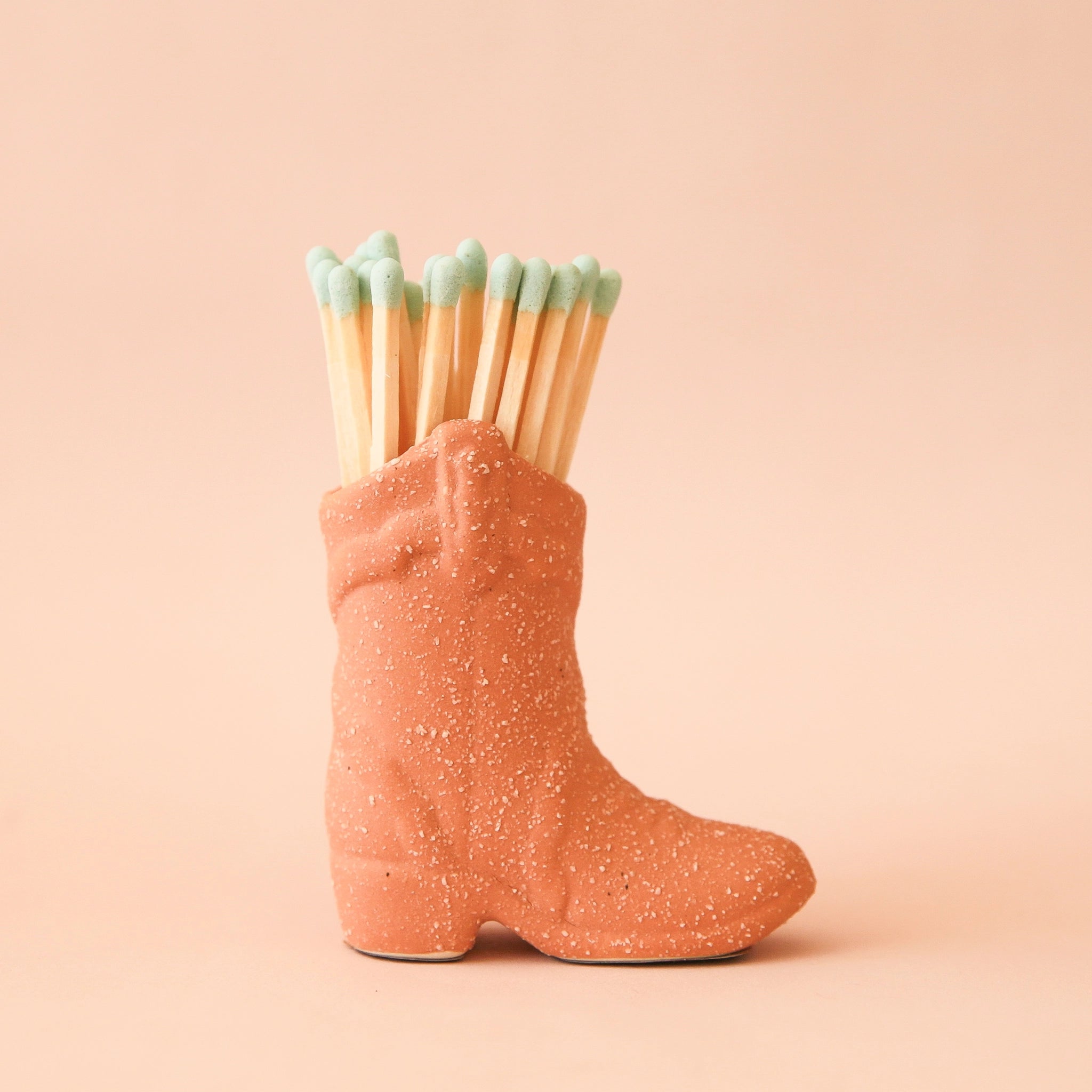 Terracotta ceramic boot match holder filled with a bundle of blue dipped matches.