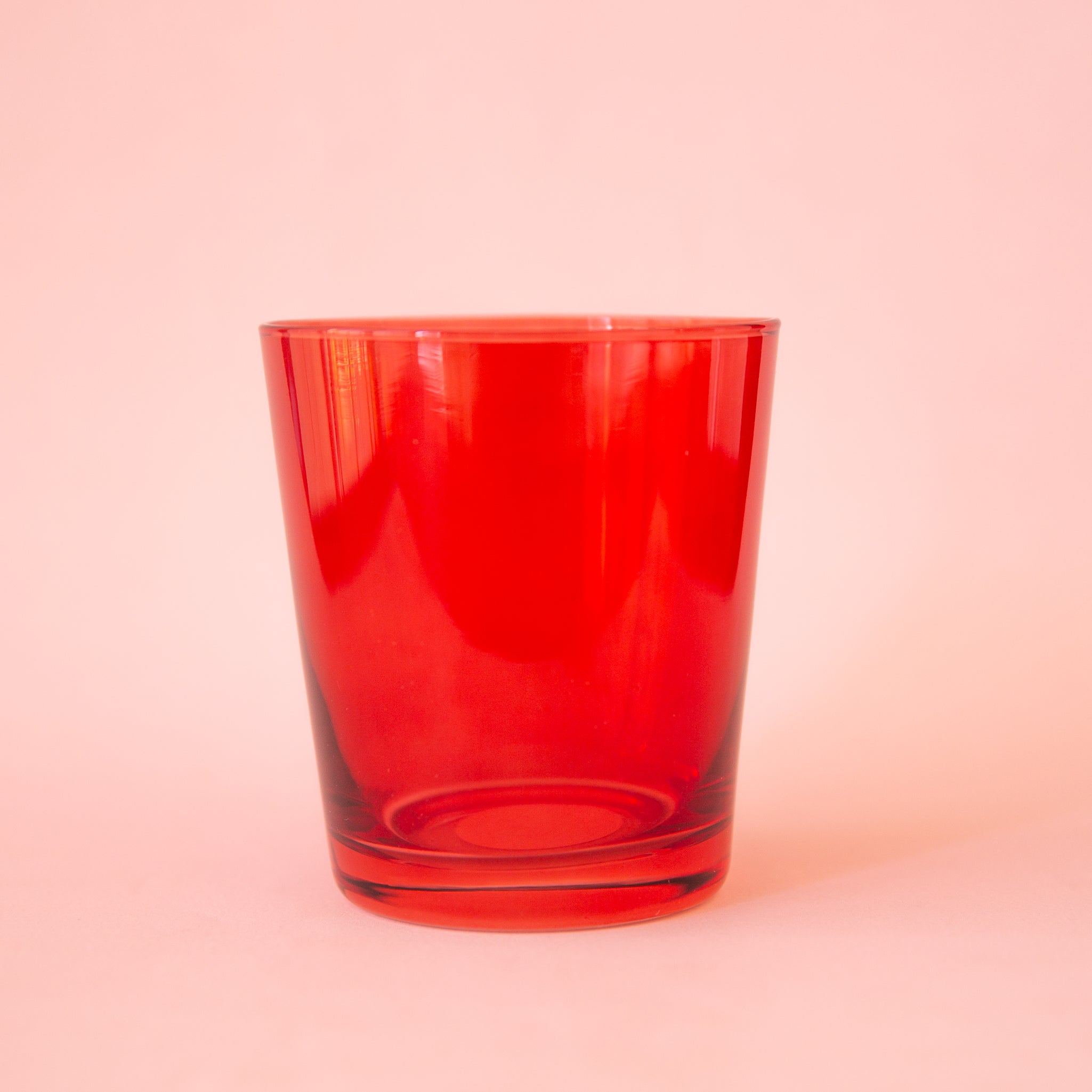 On a peach background is a short red drinking glass