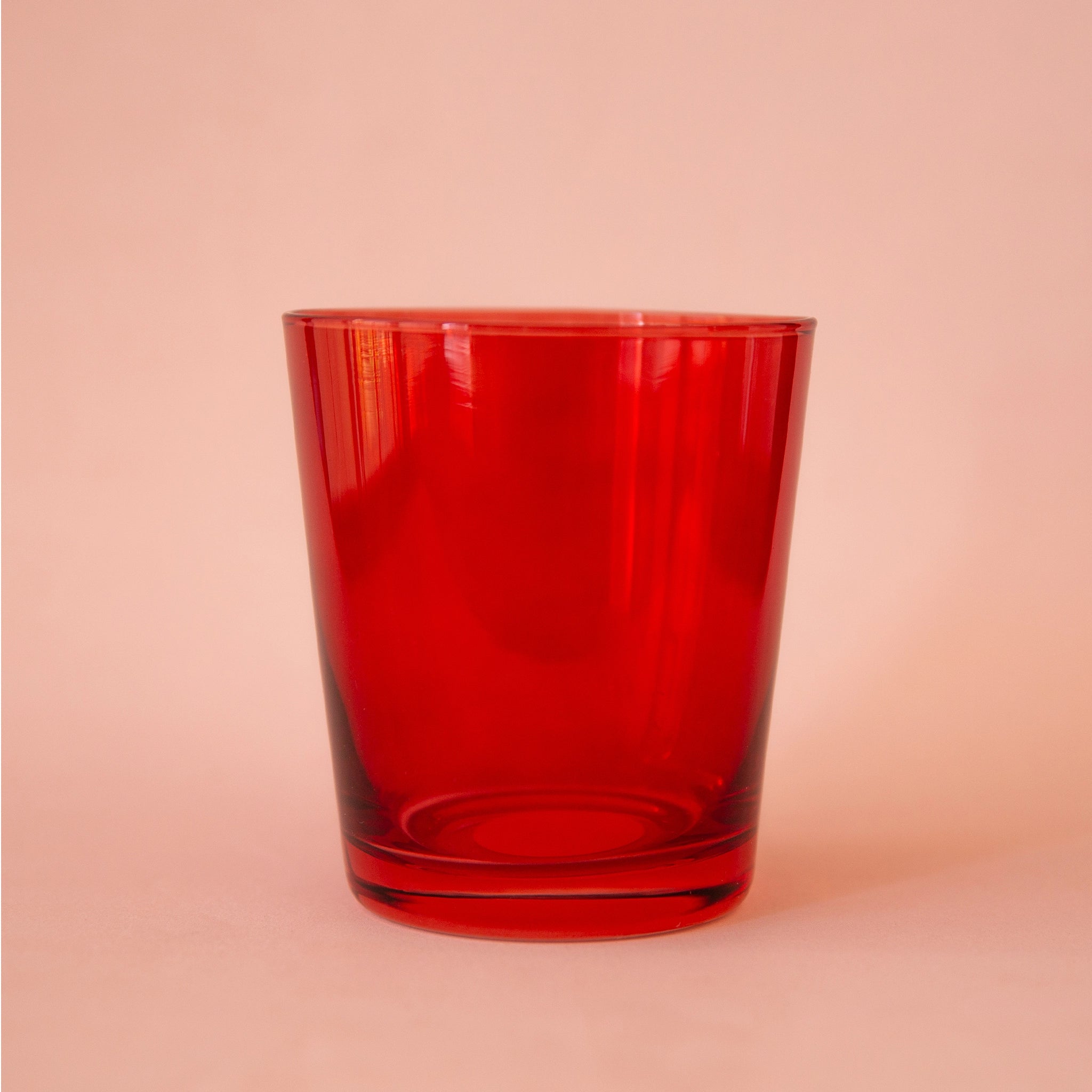 On a peach background is a short red drinking glass