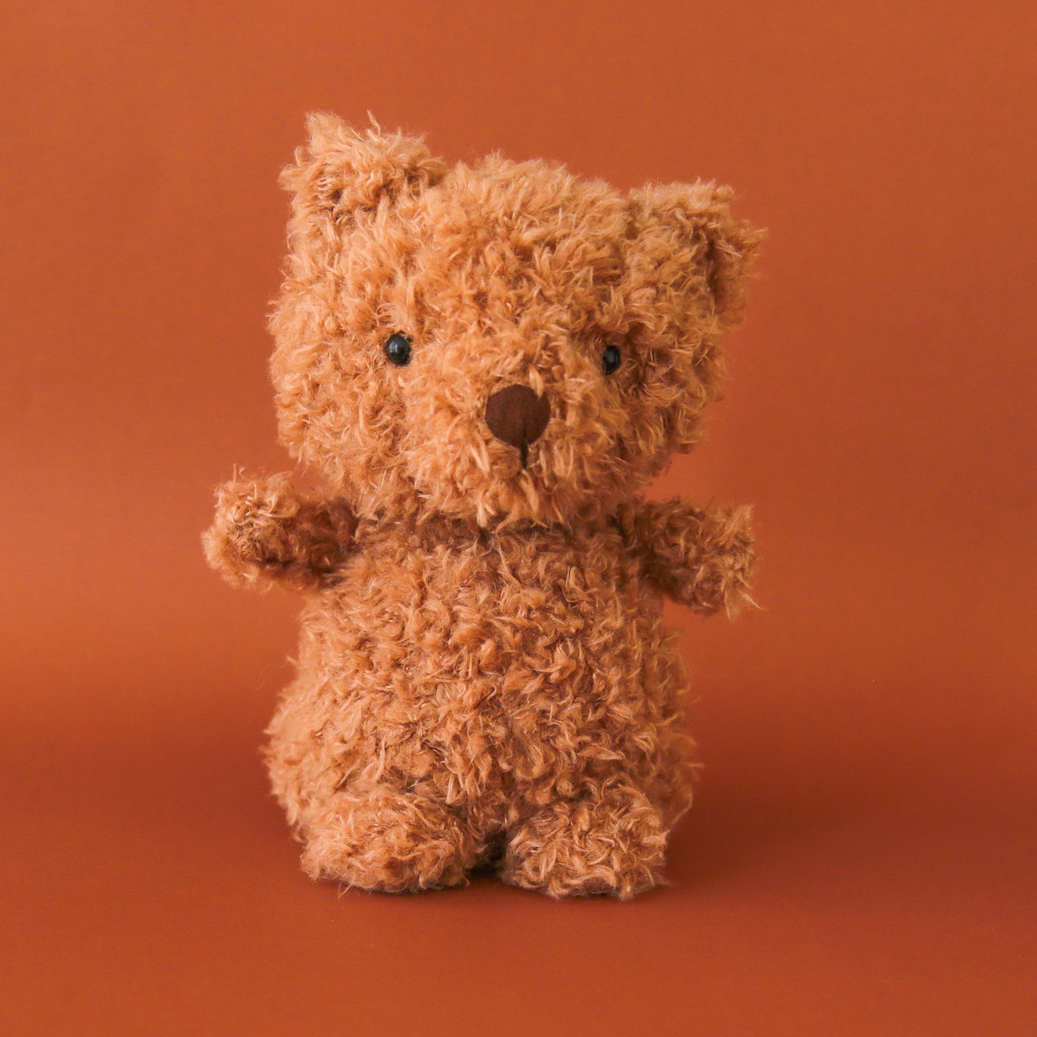 A small cuddly bear stuffed animal with chestnut brown fur, a brown nose and small little ears.