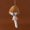 On a brown background is a  mustard yellow and white velvet mushroom shaped ornament.