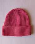 A knit beanie in a berry pink color. 