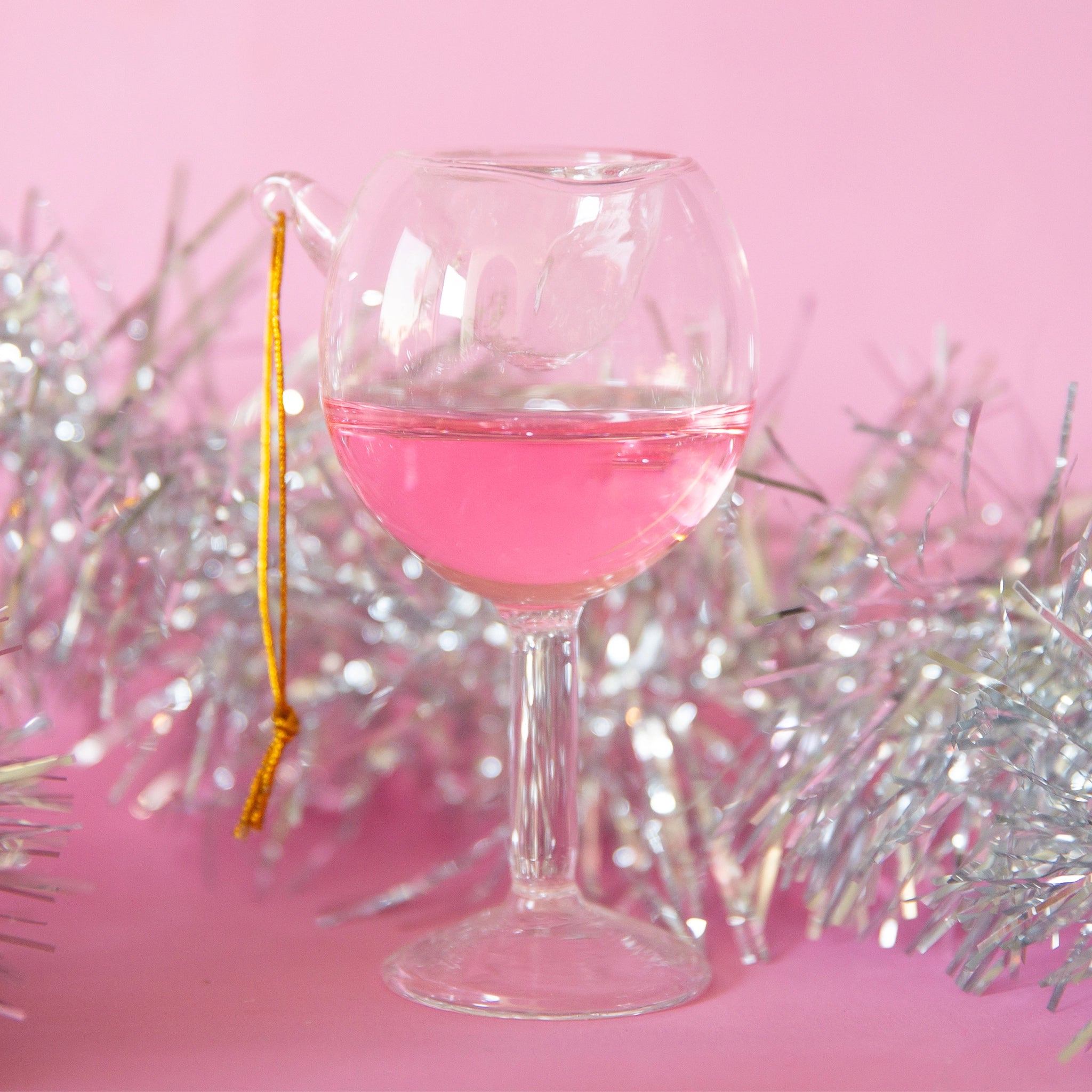 A wine glass ornament features a double lined glass with pink liquid on the inside for some movement!