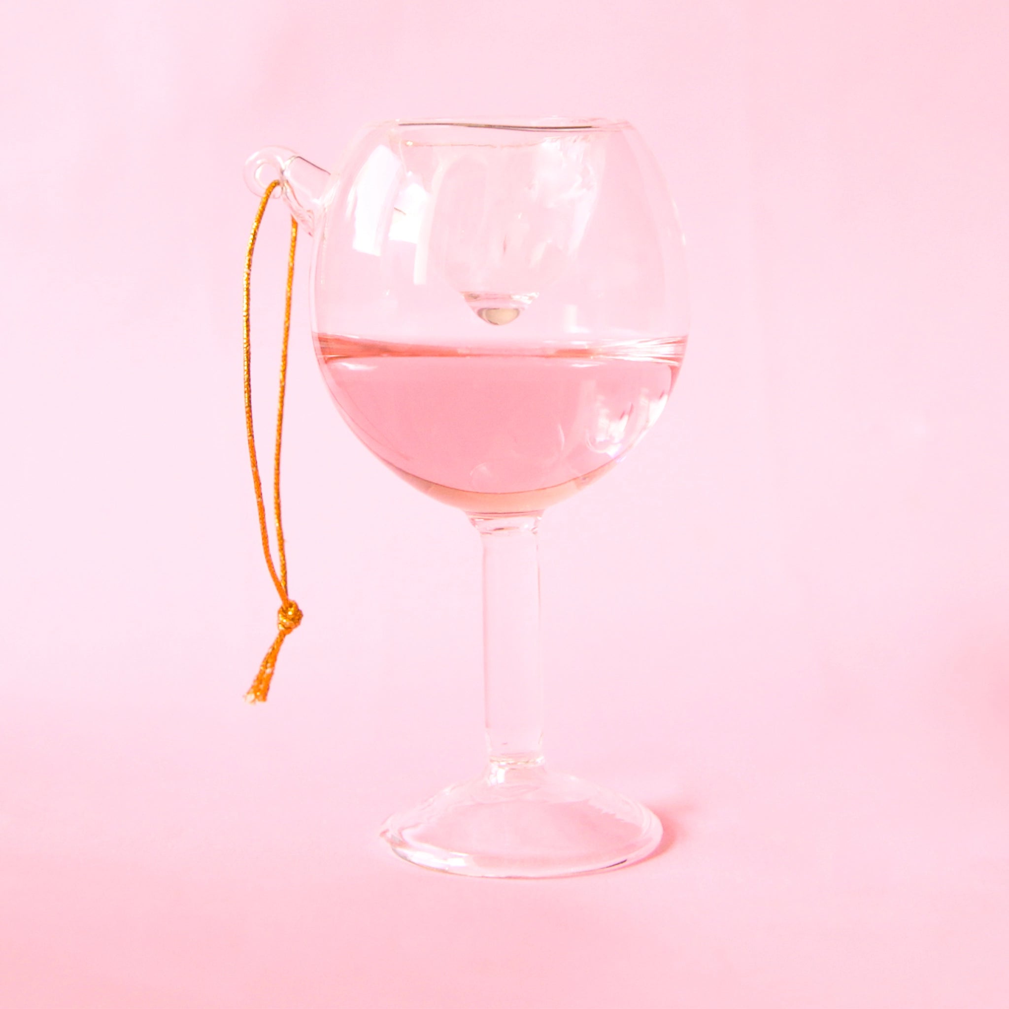 A wine glass ornament features a double lined glass with pink liquid on the inside for some movement!