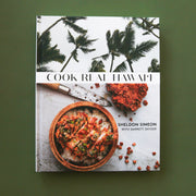 On a green background is a white book cover with palm trees and a vibrant meal in a bowl along with with text that reads, "Cook Real Hawai'i".