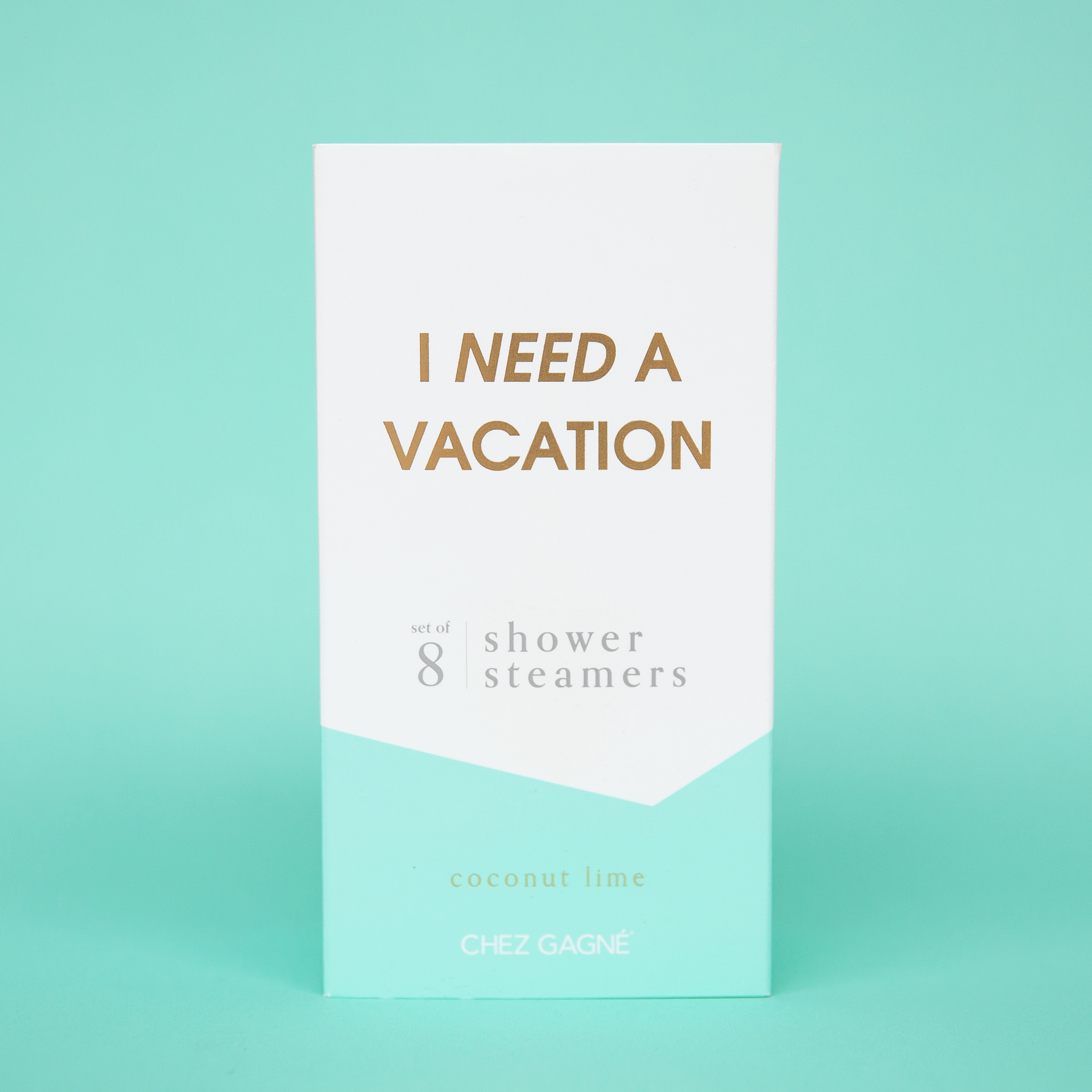 Eight white shower steaming tablets placed inside of a cardboard packaging that is teal blue and white and reads, "I Need A Vacation" in gold text.