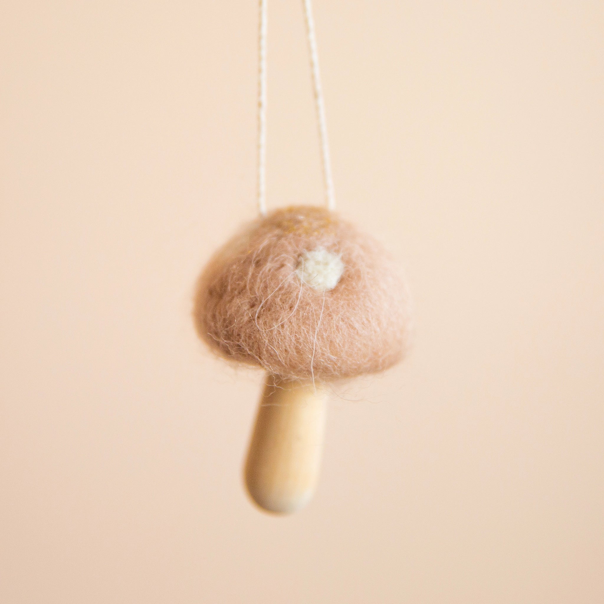 A mauve mushroom ornament with white spots and a light wooden stem.