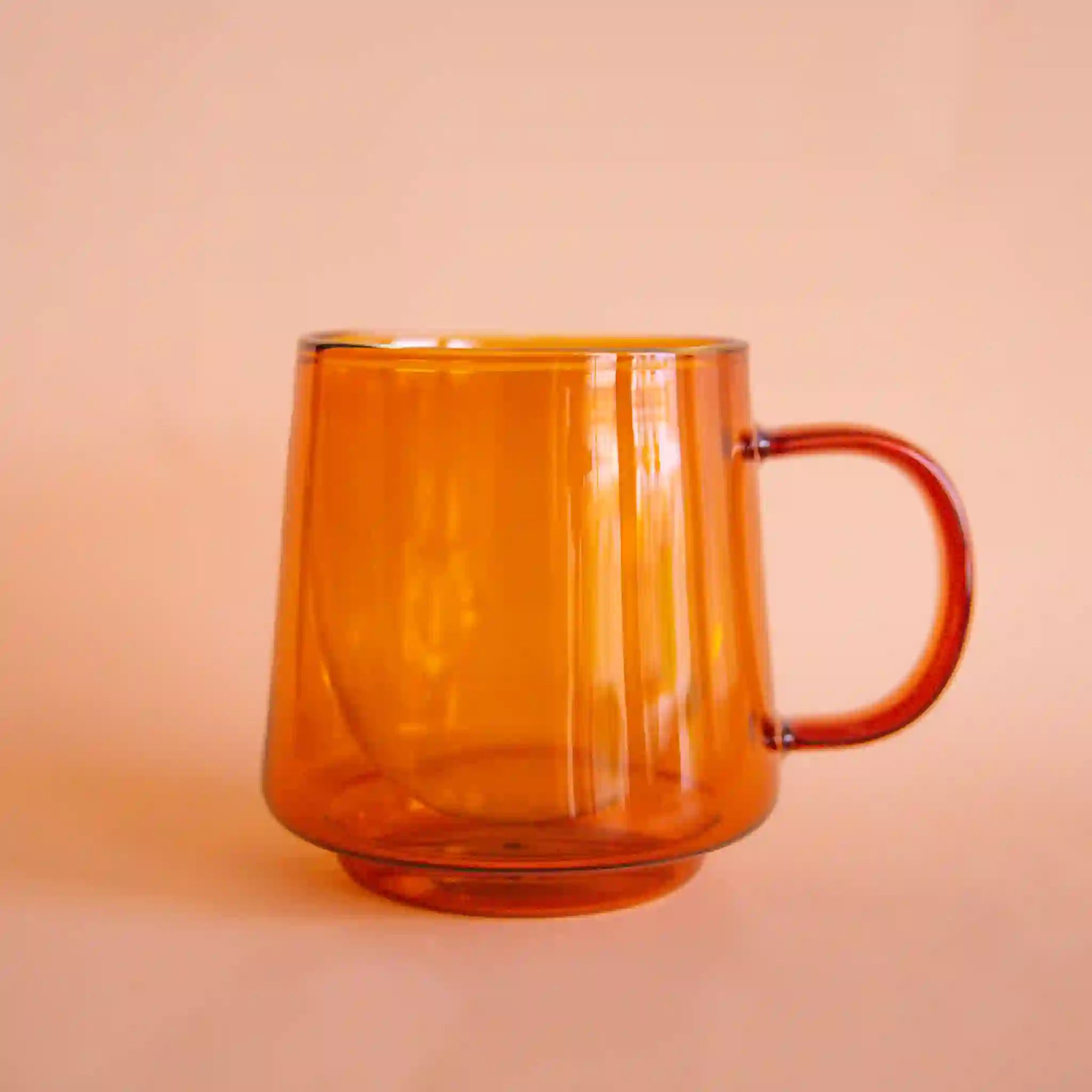 An amber glass mug featuring a double wall detail that keeps drinks insulated for longer.