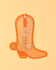 An orange cowboy boot shaped air freshener with a white string for hanging.