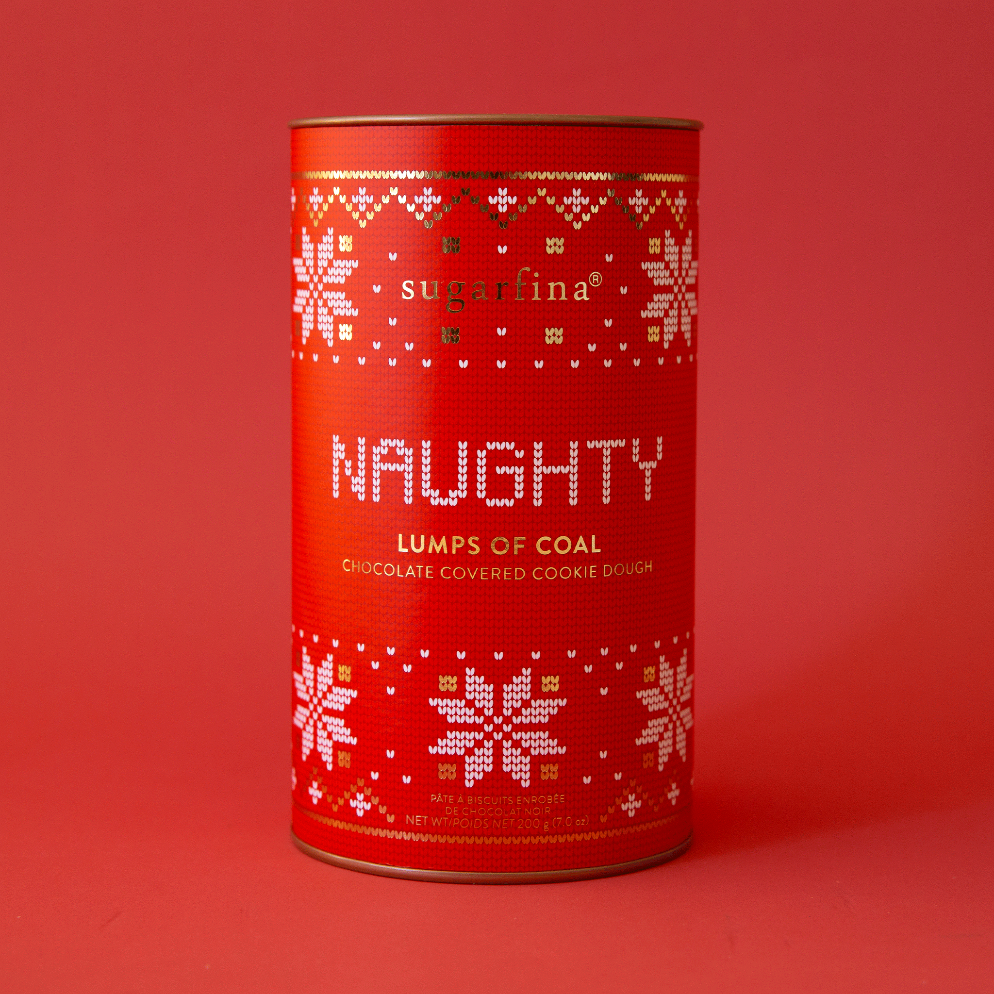 On a red background is a red canister with white snowflake designs and text that reads, "Naughty Lumps of Coal Chocolate Covered Cookie Dough".