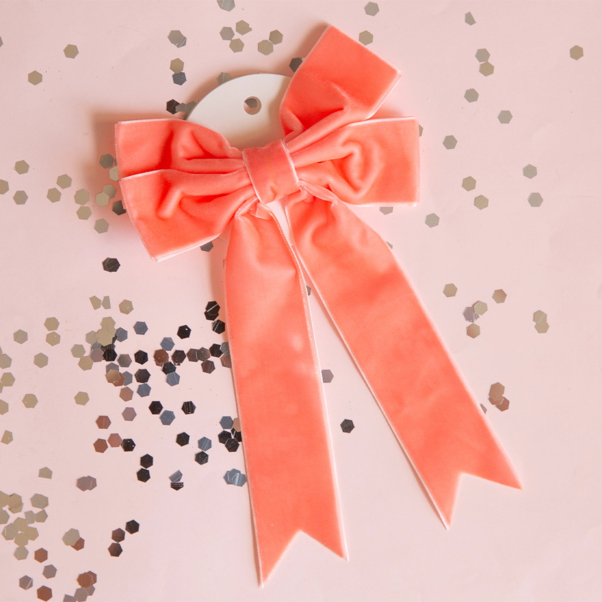 On a light pink background is a peach velvet bow.
