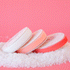 On a pink background is three spools of velvet ribbon in three different shades ranging from white to a peachy pink.