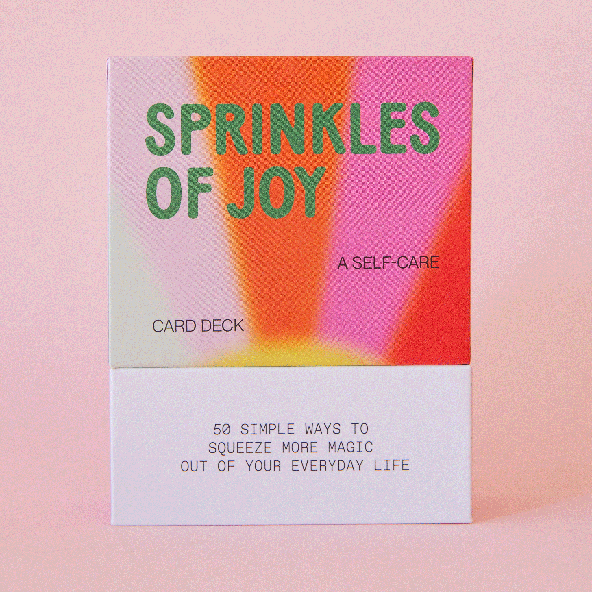 On a pink background is a deck of cards with a multicolored cover and text that reads, "Sprinkles Of Joy, A Self-Care Card Deck".