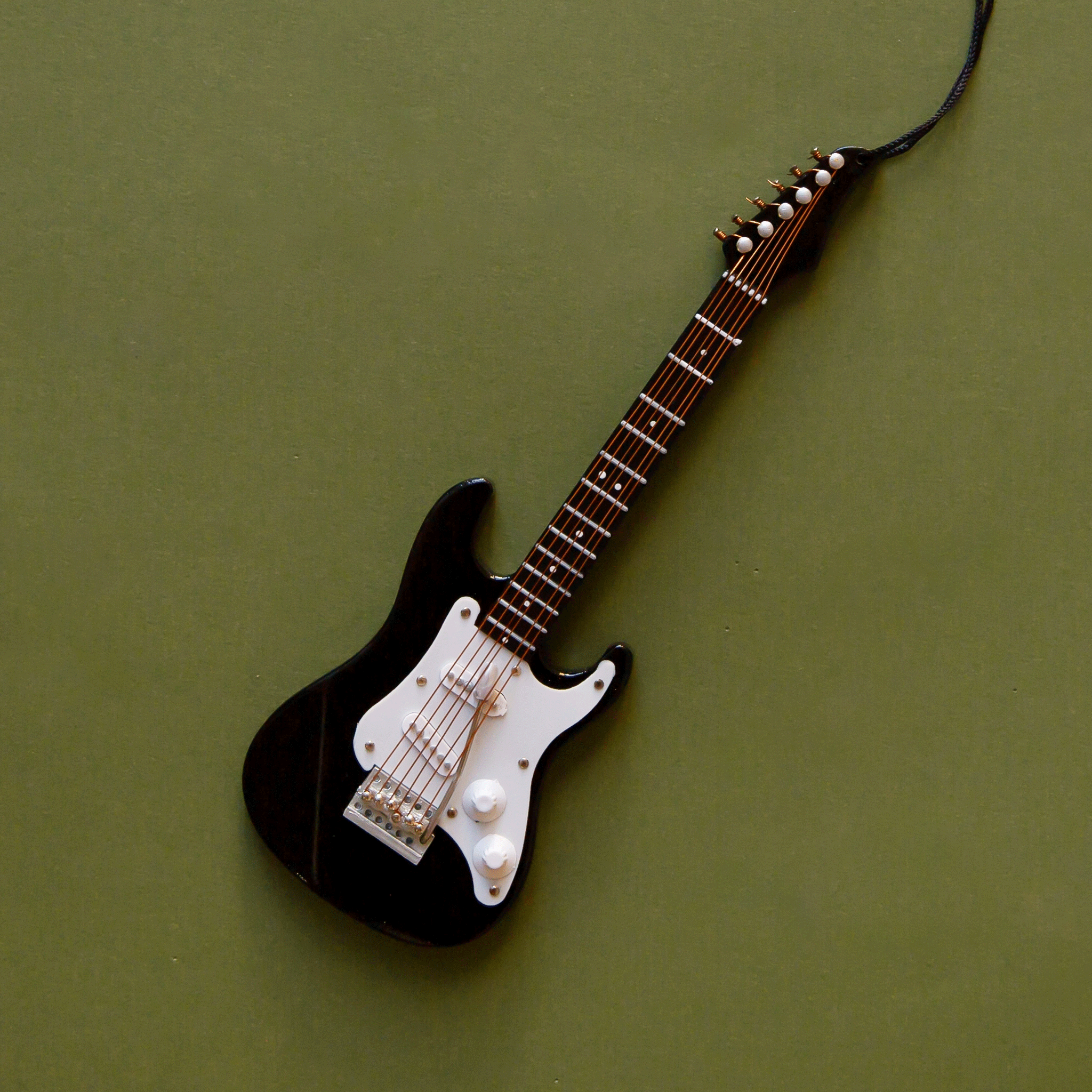 On a green background is a black electric guitar ornament.