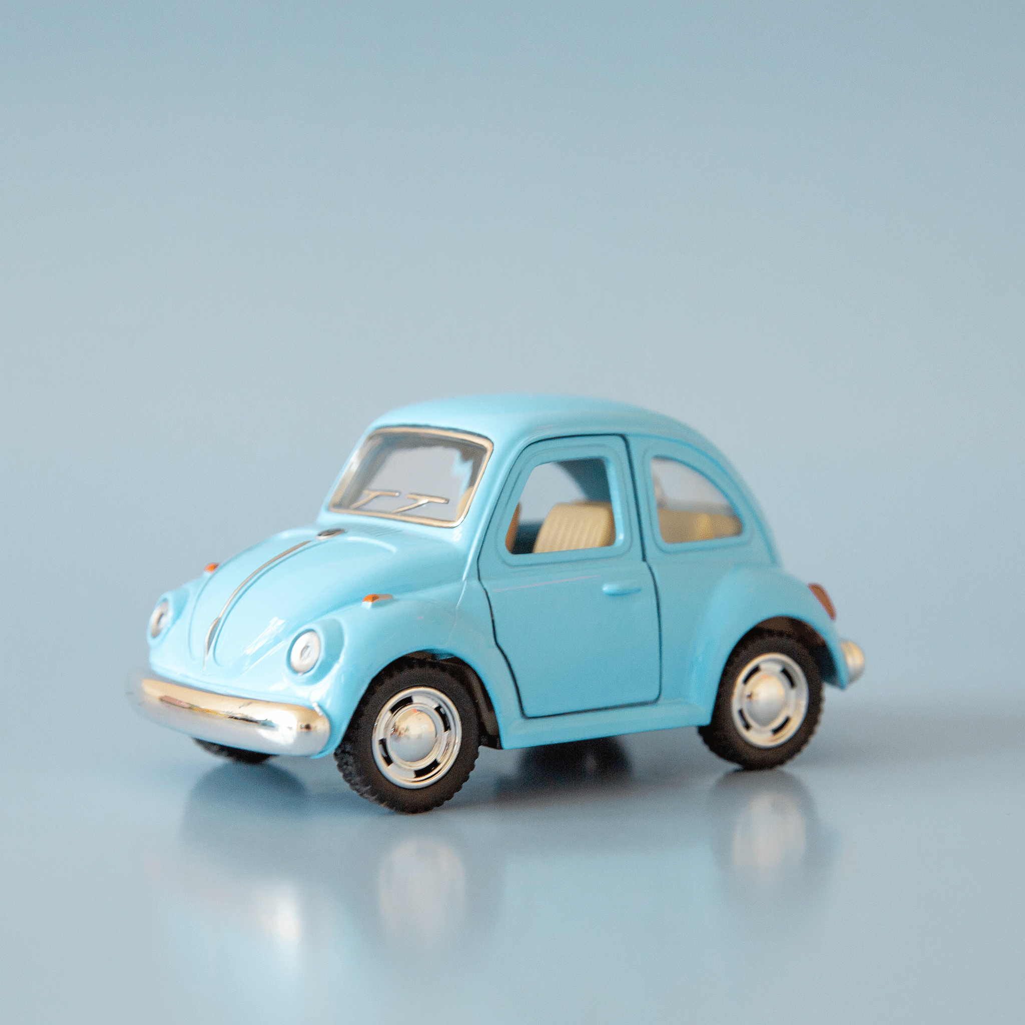 On a blue background is a blue vw bug toy. 