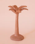 A clay colored palm tree shaped taper candle holder. 