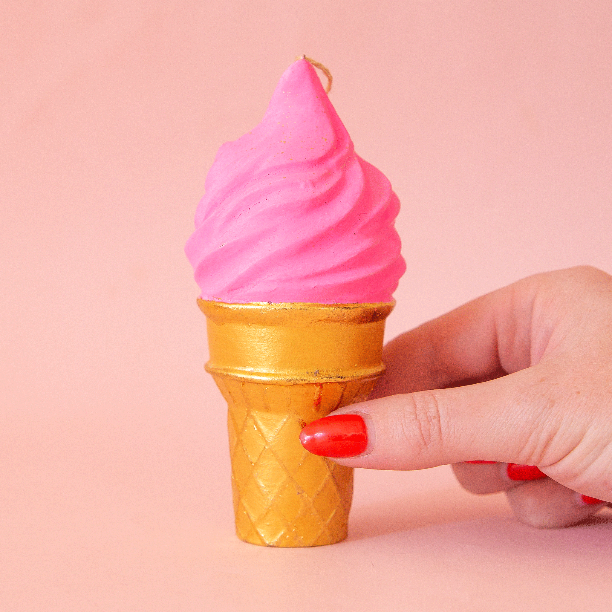 On a pink background is a dark pink ice cream cone shaped ornament.